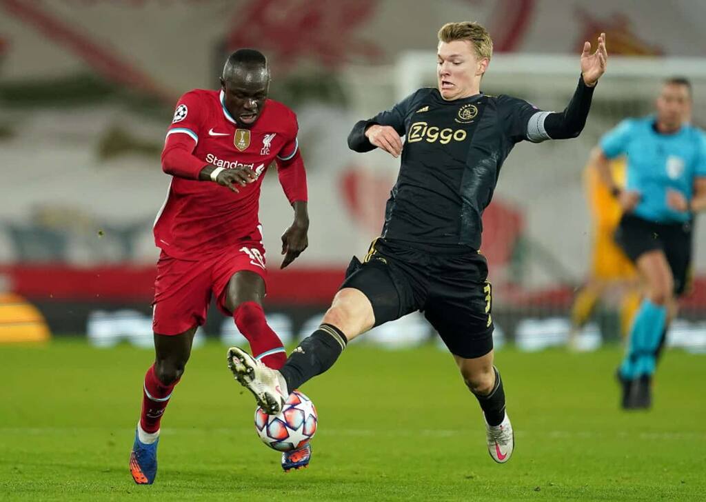 LIVERPOOL, ENGLAND - DECEMBER 01: Sadio Mane of Liverpool is challenged by Perr Schuurs of Ajax during the UEFA Champions League Group D stage match between Liverpool FC and Ajax Amsterdam at Anfield on December 01, 2020 in Liverpool, England. Sporting stadiums around the UK remain under strict restrictions due to the Coronavirus Pandemic as Government social distancing laws prohibit fans inside venues resulting in games being played behind closed doors. (Photo by Jon Super - Pool/Getty Images)