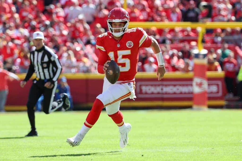 Kansas City Chiefs quarterback Patrick Mahomes scrambling while holding a football.