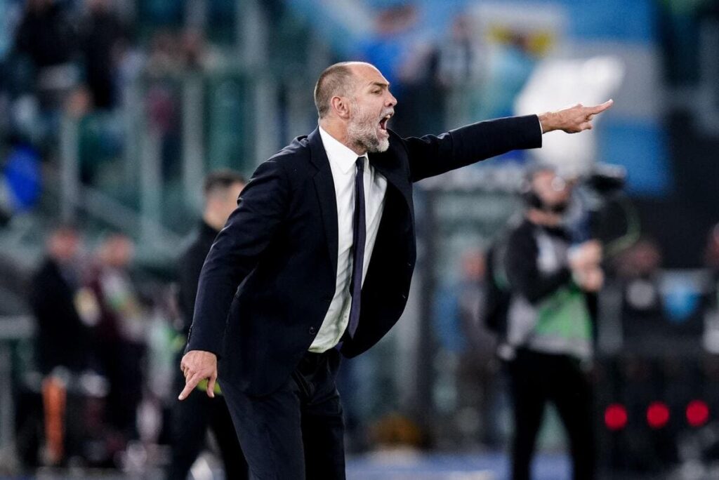 Football manager Igor Tudor wearing a suit and tie on a touchline during a game and raising his left arm to point