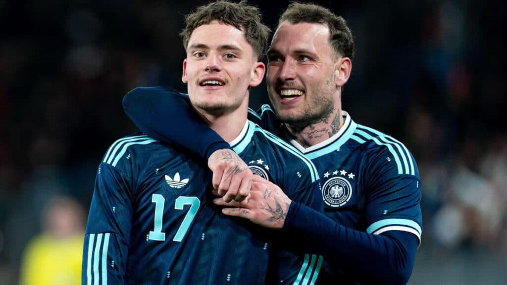 Florian Wirtz celebrating a goal for the Germany national football team in a green shirt with his number 17 squad number on it while being embraced by a teammate