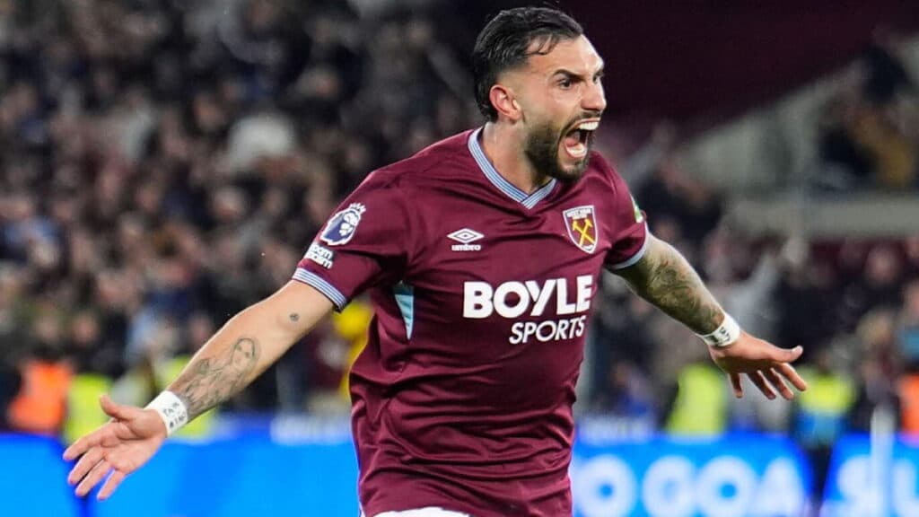 West Ham United Football Club footballer Taty Castellanos celebrates scoring their side's third goal of the game during a Premier League match at London Stadium, wearing a purple top with claret trim, opening his mouth and spreading his arms on a pitch with fans blurrily visible in the background