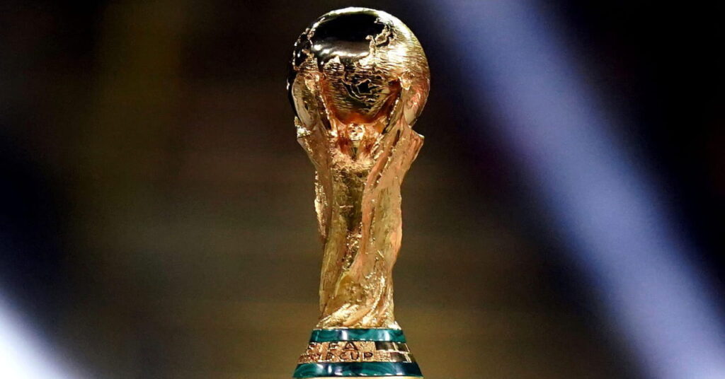 Uma foto do troféu dourado da Copa do Mundo de Futebol da FIFA em uma praça sob os holofotes