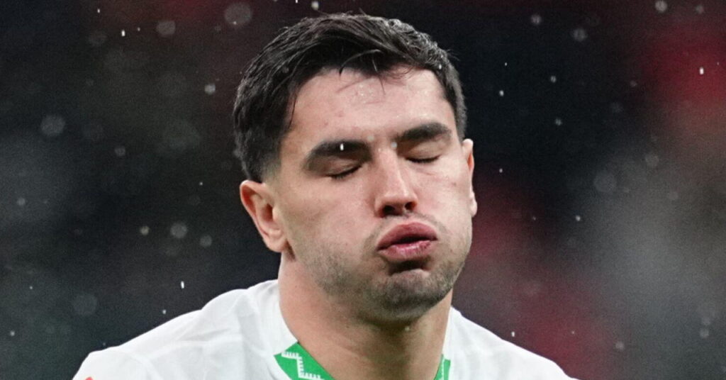 Football Brahim Diaz playing for the Morocco national football team while closing his eyes and exhaling on a pitch in a white shirt with green trim and his number 10 in red in the centre of the shirt
