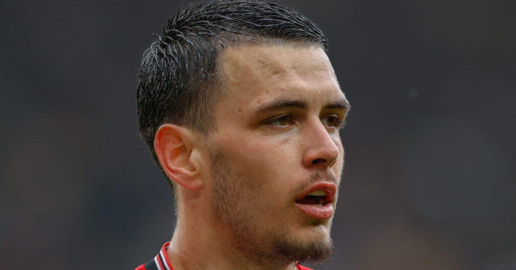 O jogador de futebol Enzo Le Fee joga pelo Sunderland Football Club enquanto olha para a esquerda em um campo de um estádio vestindo uma camisa vermelha e branca.