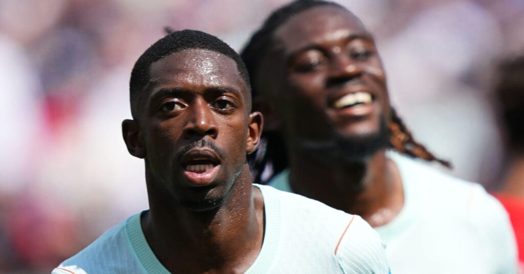 O jogador de futebol Ousmane Dembele corre para comemorar um gol em campo enquanto sorri com uma camisa branca da seleção francesa de futebol com um companheiro de equipe indistintamente visível atrás dele na Copa do Mundo de 2026
