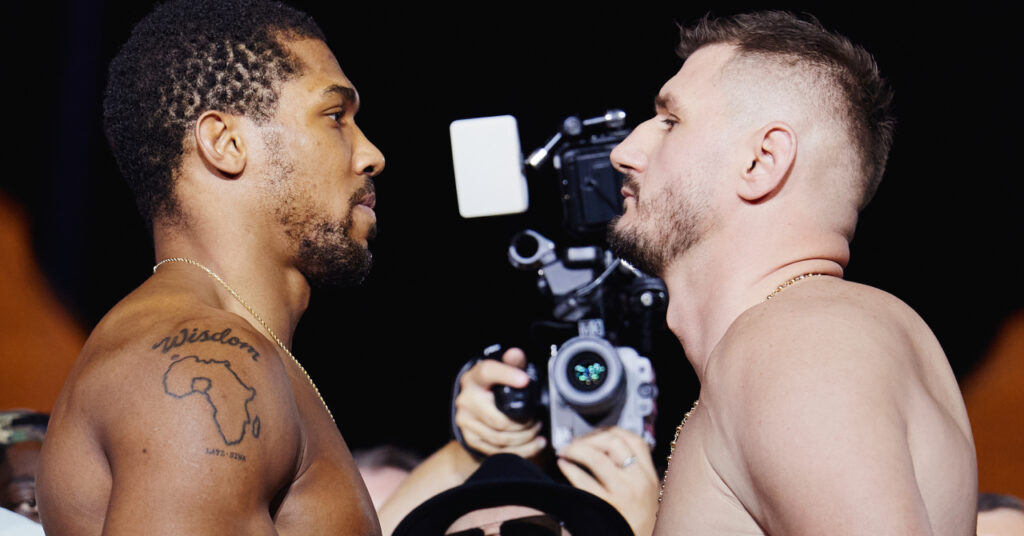 O boxeador Anthony Joshua e o adversário peso pesado do boxe Cristian Prenga se enfrentam antes da luta, com Joshua à esquerda olhando para a direita e Prenga à direita para a esquerda