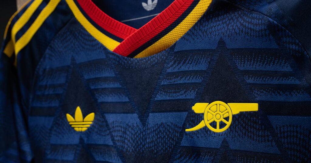 A close-up of Premier League side Arsenal Football Club's 2026/27 away kit in a navy, yellow and red shirt