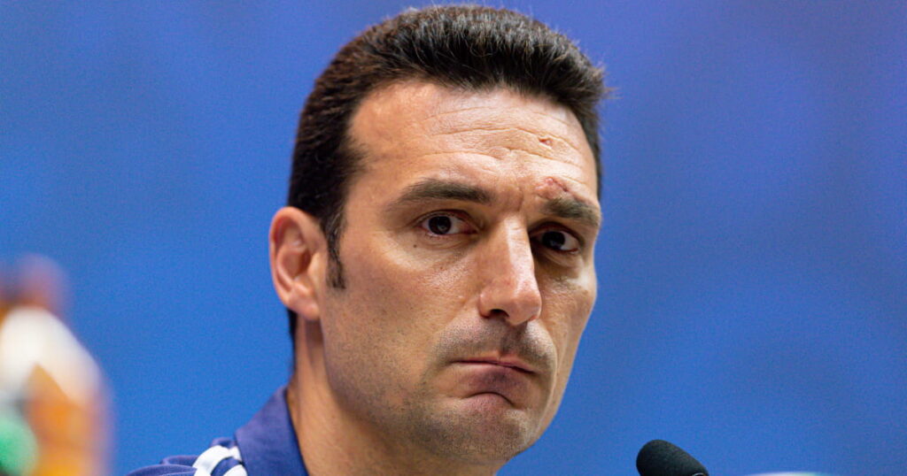 Football manager Lionel Scaloni looking intently ahead at a press conference as the Argentina head coach sits in front of a microphone and football