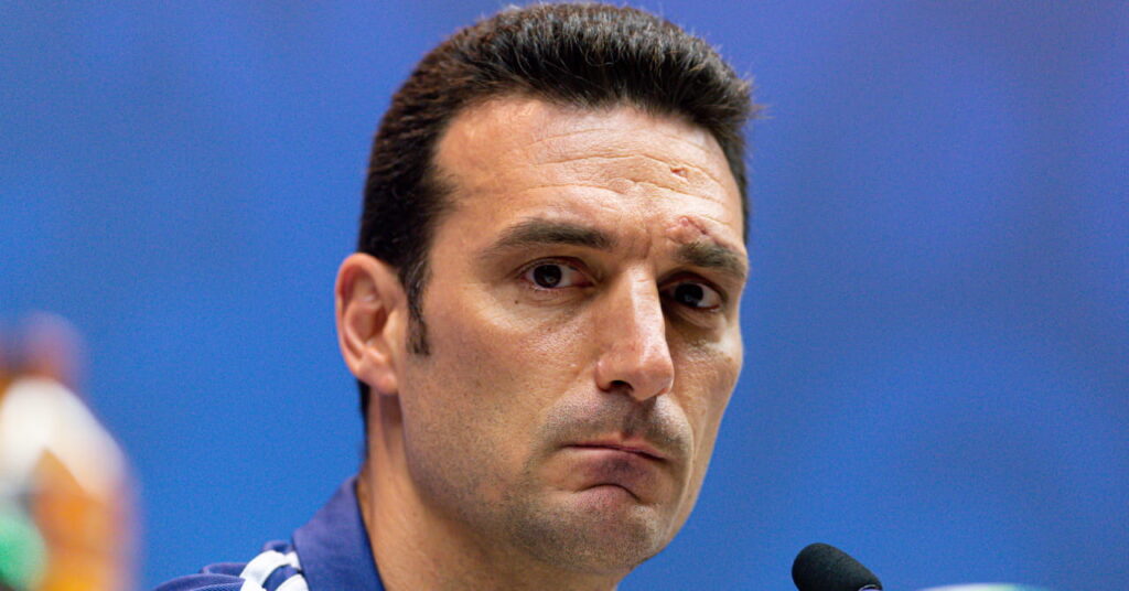 Football manager Lionel Scaloni looking intently ahead at a press conference as the Argentina head coach sits in front of a microphone and football