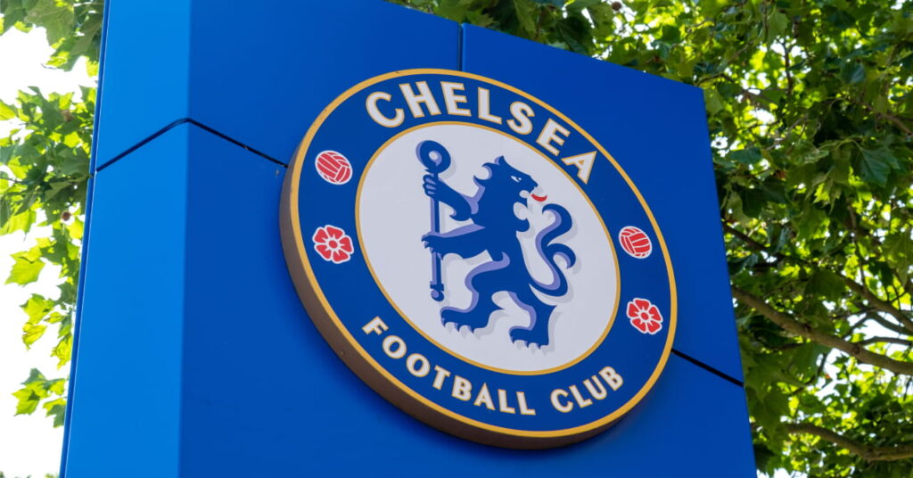 A blue square sign under a tree featuring the circular Chelsea Football Club emblem of a lion