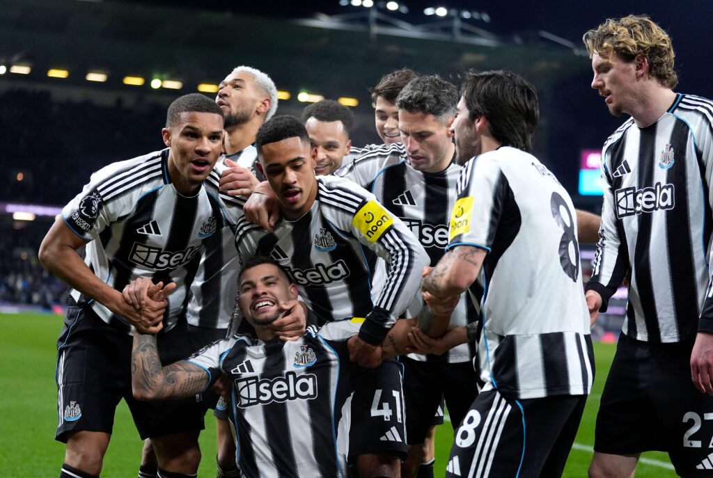 Brazil footballer Bruno Guimaraes smiling and celebrating a goal for Premier League team Newcastle United Football Club while wearing a black top with white trim and the club badge on the chest