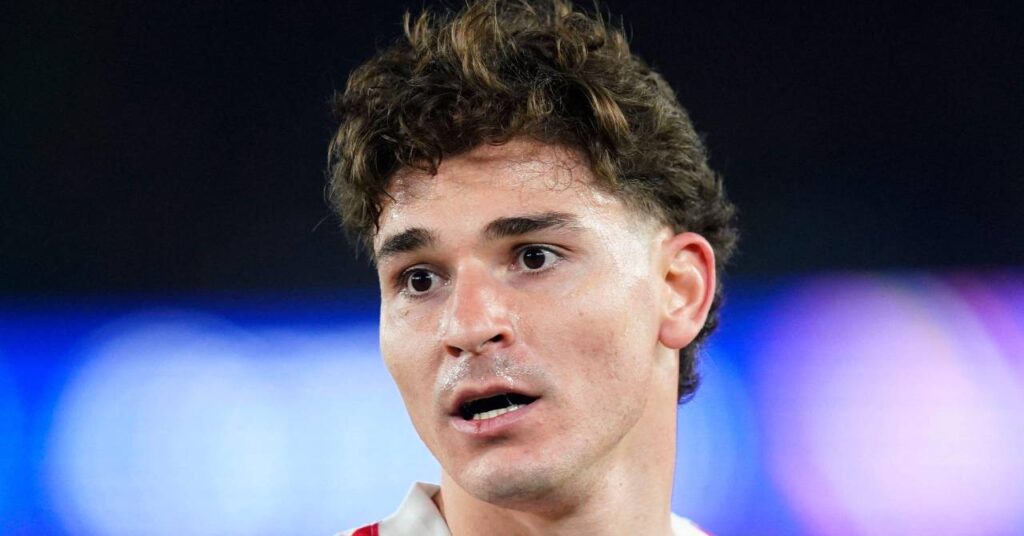 Argentina footballer Julian Alvarez looking to his right while playing in a stadium for La Liga team Atletico Madrid Football Club in a red and white shirt