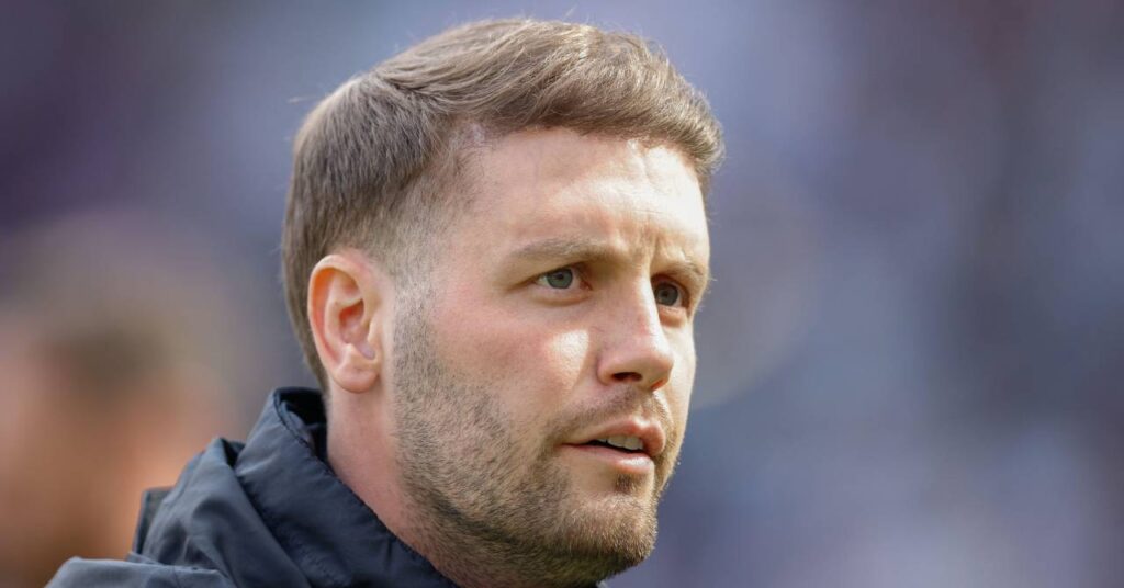 Football manager Fabian Hurzeler looking to his left while the head coach of Premier League team Brighton and Hove Albion is wearing a black coat