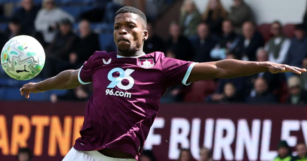 Footballer Florentino Luis of Premier League team Ipswich Town Football Club shaping to hit a ball with both arms outretched while playing for Burnley at their Turf Moor stadium in their home colours of predominantly claret and looking at a white ball in the air