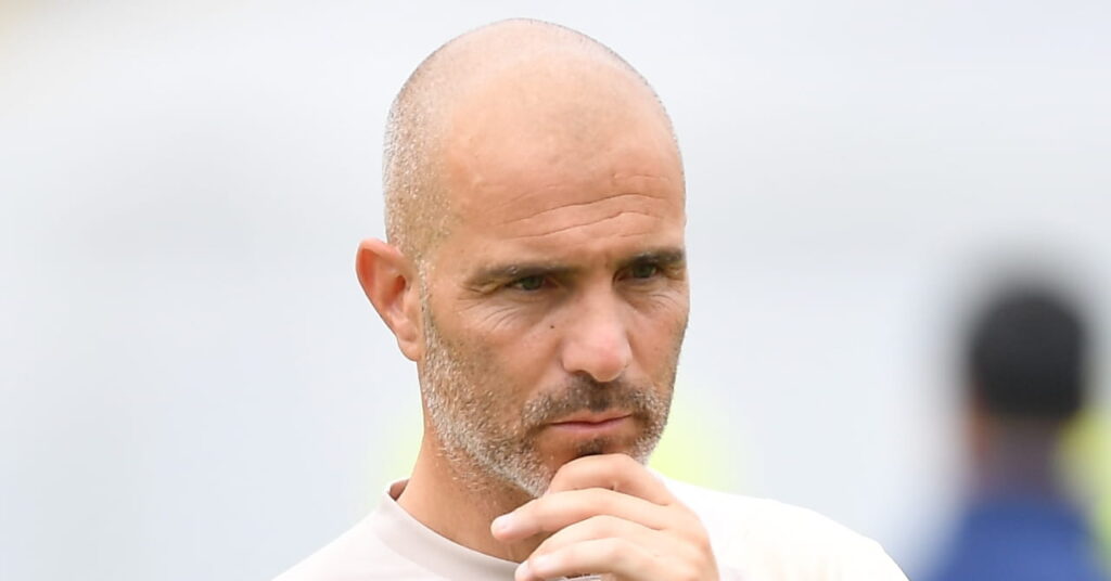 Football manager Enzo Maresca holding his chin during a training session held by the head coach while he wears a light-coloured top