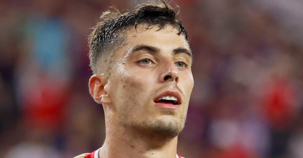 Germany footballer Kai Havertz holding his arms out in celebration while playing for Arsenal Football Club in their predominantly red and white primary colours with a crowd blurrily visible in the background