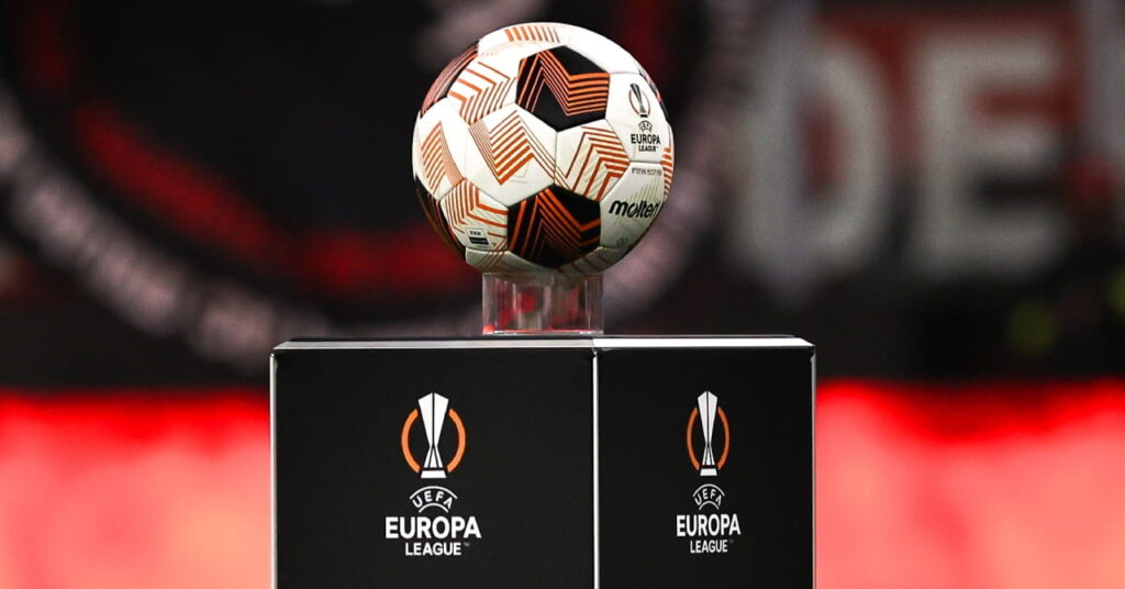 Bola laranja e branca da competição europeia de futebol UEFA Europa League com a palavra derretida no meio num pedestal num estádio