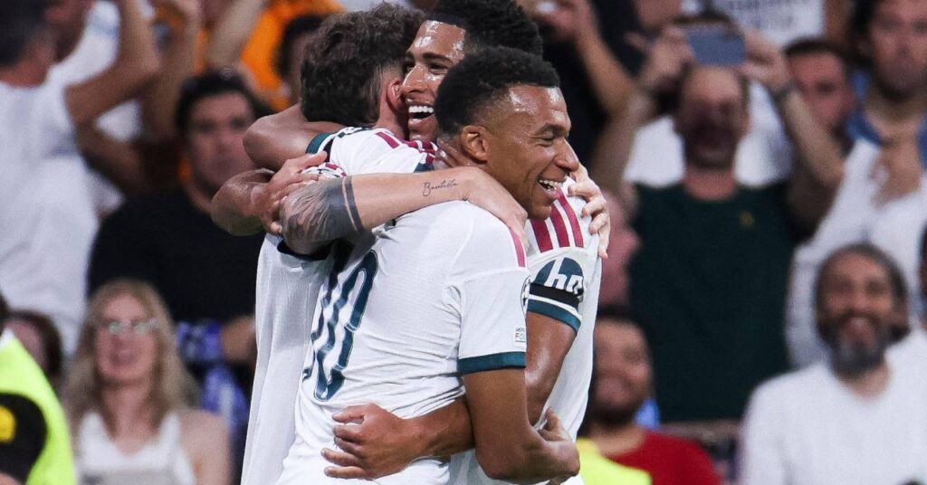 England and France footballers Kylian Mbappe and Jude Bellingham embracing and celebrating a goal while playing for Spanish La Liga team Real Madrid Football Club in a white kit with green and red trim with their names and numbers on the back of the shirts in green
