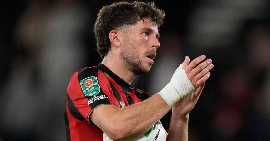 Scotland footballer Ryan Christie applauding and carrying the match ball after scoring a hat trick of three goals for Bournemouth while wearing and red and black striped shirt with white strapping on his right wrist