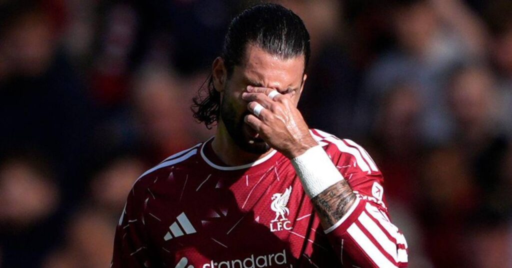 Hungary footballer Dominik Szoboszlai holding his left arm to his eyes while playing for Premier League team Liverpool Football Club in a red Adidas shirt with white details in a stadium