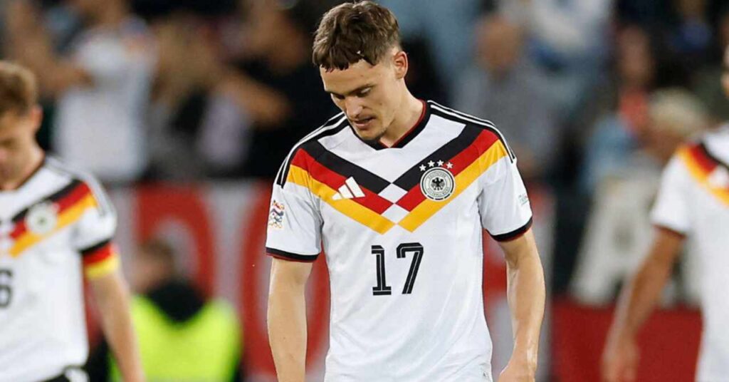 O jogador de futebol do Liverpool, Florian Wirtz, vestindo o uniforme da seleção alemã com detalhes pretos e listras pretas, vermelhas e amarelas no peito e seu número 17 em preto na frente