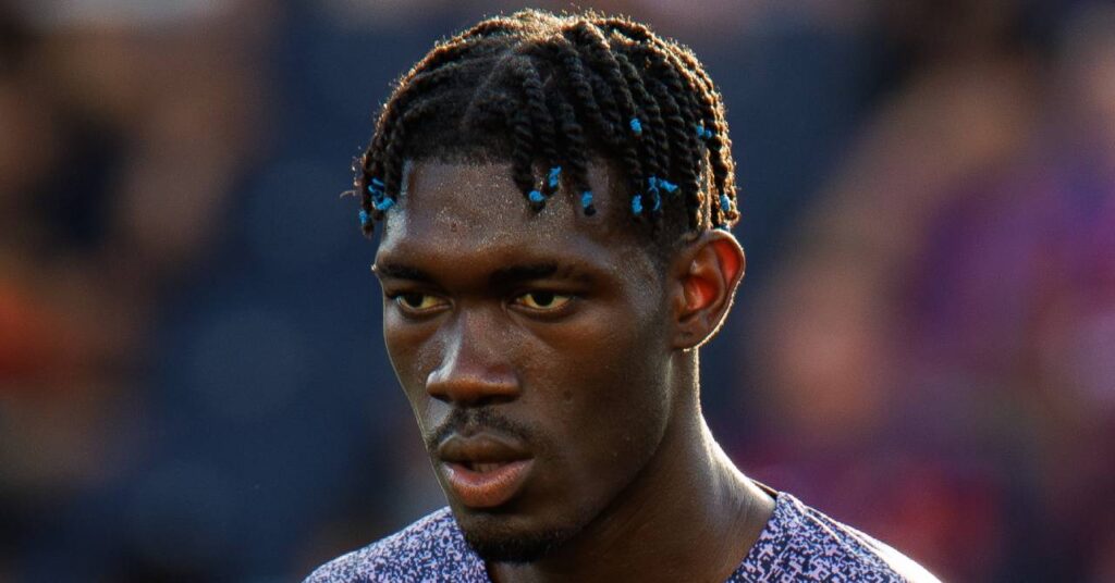 Mali footballer Yves Bissouma playing football in a stadium in a pink and dark blue shirt